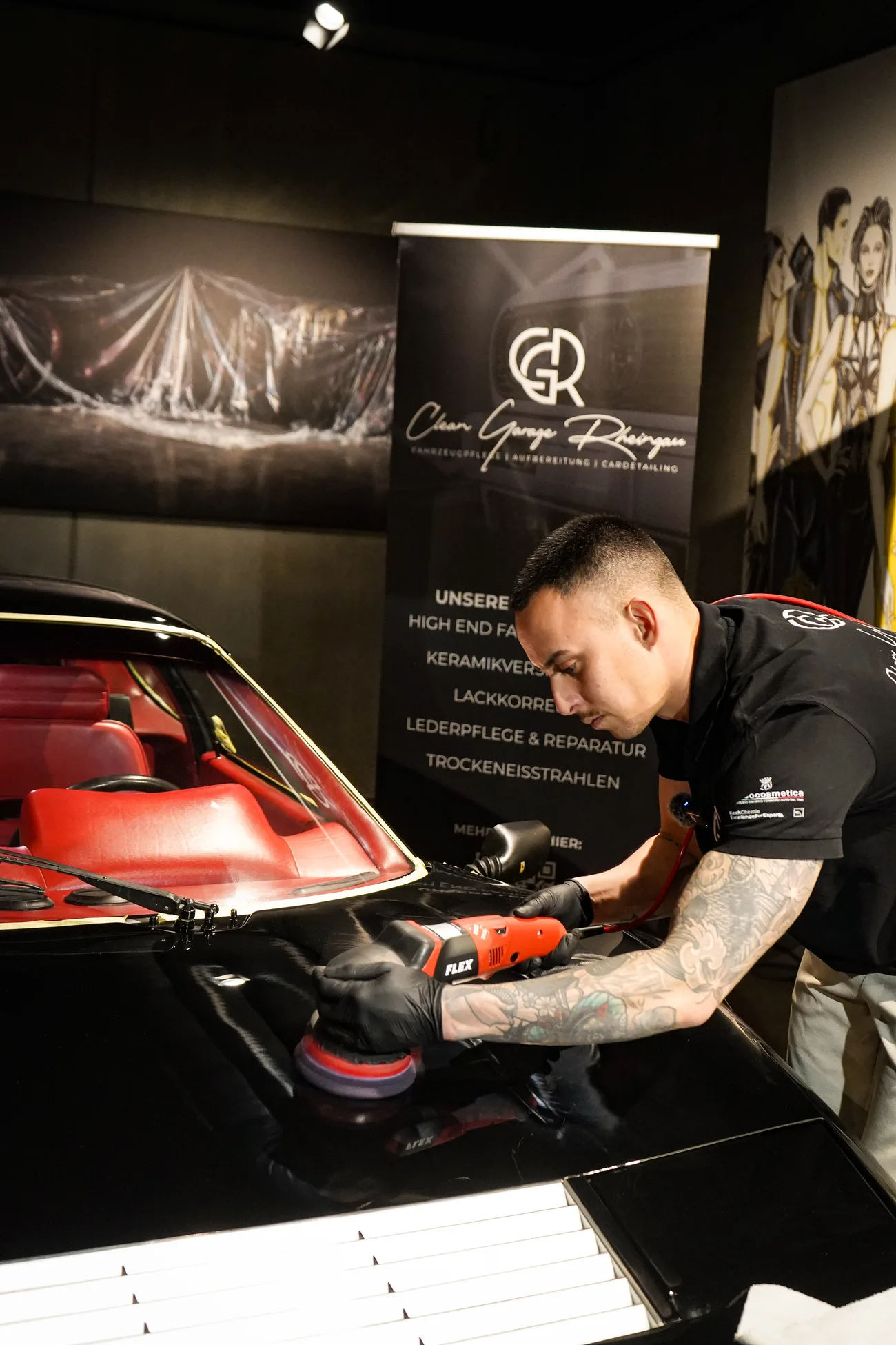 Detailer von Clean Garage Rheingau poliert eine Motorhaube neben dem CGR-Banner