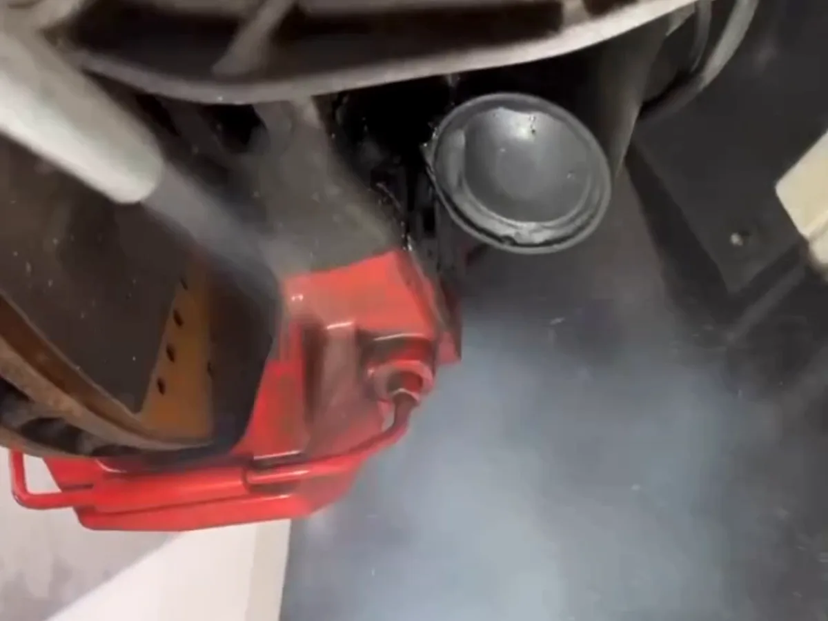 Roter Bremssattel im Radhaus, Trockeneisstrahl mit dichter CO₂-Nebelwolke