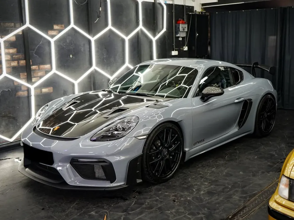 Grauer Porsche 718 GT4 RS in der Halle, Details von Heckflügel und Schriftzug